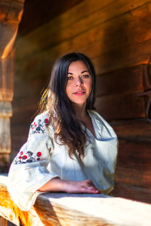 Young woman in ukrainian national costume at the wooden sunparlourの写真素材