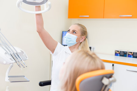 Woman doctor dentist in white costume with a patient - setting the lightの写真素材