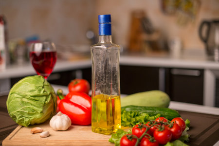 Close up photo of the bottle of sunflower oil on the table near fresh salad vegetables -  garlic, tomatoes, cucumber, cabbage, zucchini and pepperの写真素材