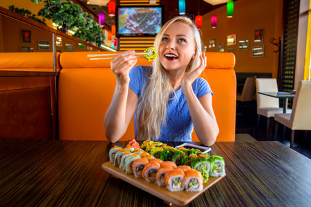 Woman eats traditional sushi rolls at the restaurant - close up photo.の写真素材