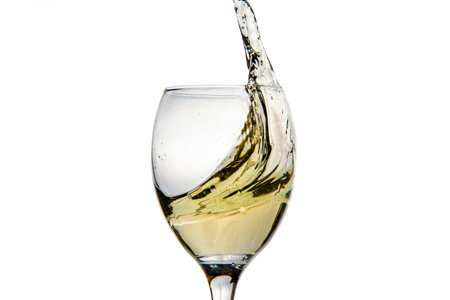Wineglass with splashing drops of champagne - motion freeze close-up picture isolated on the white background.の写真素材