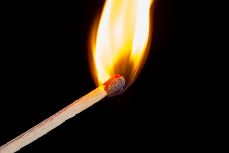 Burning match isolated on black background with smoke clouds. Macro photo.