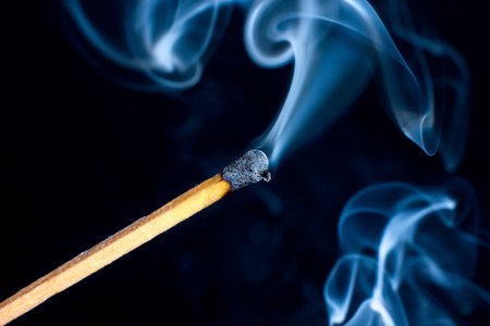 Burning match isolated on black background with smoke clouds. Macro photo.の写真素材