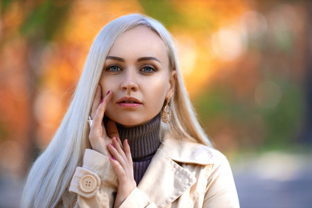 Beautiful girl posing on the street in the autumn park in the light of setting sun. Beauty close up portrait.の写真素材