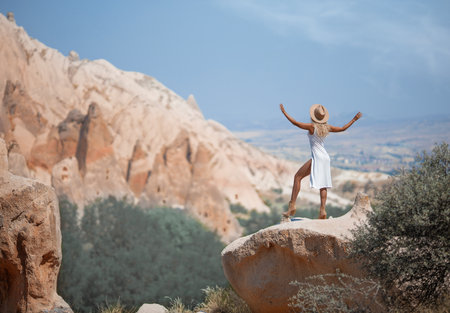 Beautiful girl in a hat and with perfect legs posing in Cappadocia mountain canyon. Traditional nature desert landscape.の写真素材