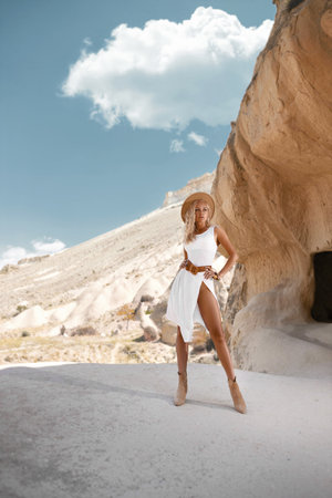 Beautiful girl in a hat and with perfect legs posing in Cappadocia mountain canyon. Traditional nature desert landscape.の写真素材