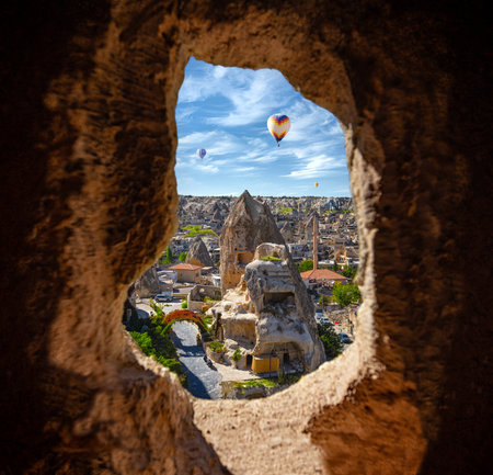 Cappadocia's beautiful view through the window hole - a morning landscape view with sunrise flying balloons and cave castles. Conceptual photo about freedom and hope.の写真素材