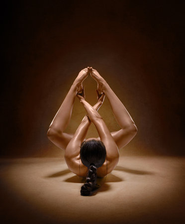 Beautiful nude sexy fitness girl with great figure flexing her perfect body in a yoga pose at the studio. Spider pose.の写真素材