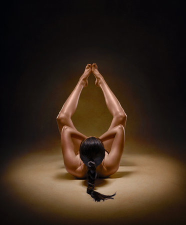 Beautiful nude sexy fitness girl with great figure flexing her perfect body in a yoga pose at the studio.の写真素材