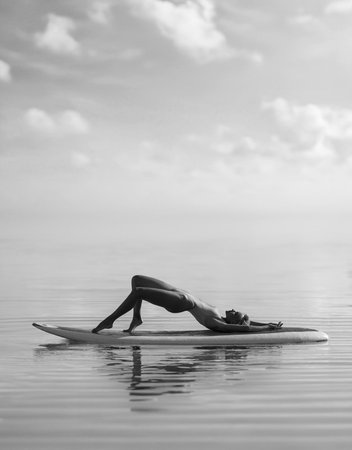 Beautiful fitness girl with a perfect butt and body posing outdoor in the calm open sea on the...