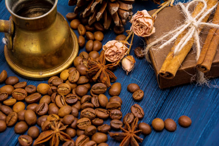 Coffee beans, anise, cinnamon, turk, present box and cones on dark blue wooden background. Christmas evening backgroundの写真素材
