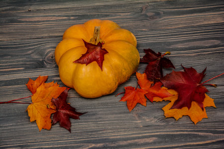 Pumpkin with maple leaves on wooden background. Autumn cardの写真素材