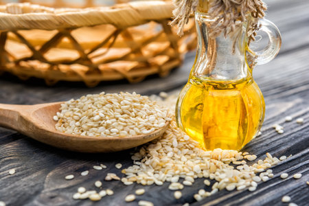 Sesam oil in bottle, sesam seeds, spoon on wooden backgroundの写真素材