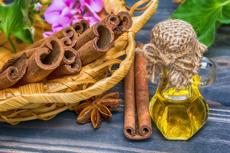 Essential cinnamon oil in bottle and cinnamon cticksの写真素材