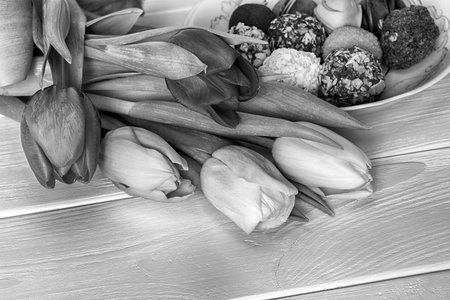 Tulips bouquet and homemade chocolate candys wooden background. Black and white