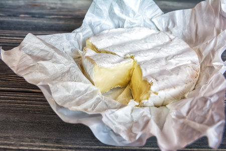Camembert cheese on white paper and rustic dark wooden background. Top viewの写真素材