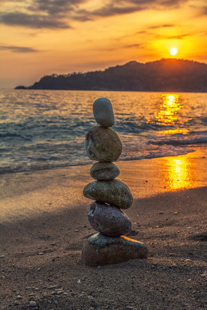 Zen stone tower on the beach. Sea and mountain on sunset backgroundの写真素材