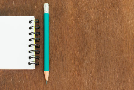 white note book with pencil on wooden boardの写真素材