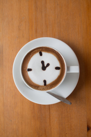 Close up of A Cup hot latte art coffee drawn an oclock business concept on wooden table.の写真素材