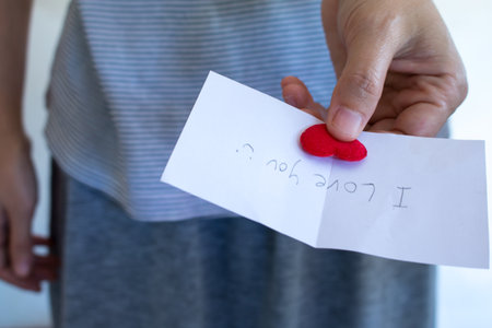 Asian woman is showing valentine's card with red heart.の写真素材