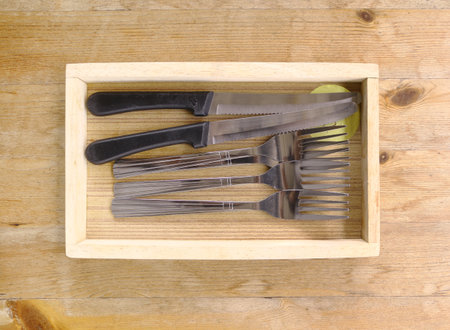 Forks and knifes in wooden tray.の写真素材