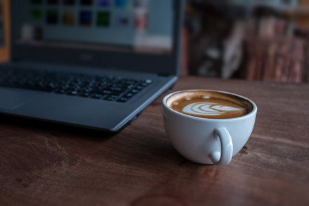 Close up of Cup of hot latte art coffee with laptop computer on wooden table, work with coffee concept picture foe business background.の写真素材