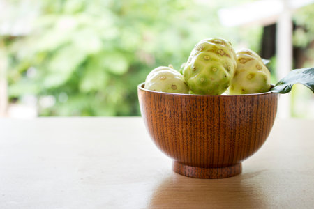 Noni or Morinda citrifolia, great morinda, Indian mulberry, beach mulberry, or cheese fruit on wood table.の写真素材
