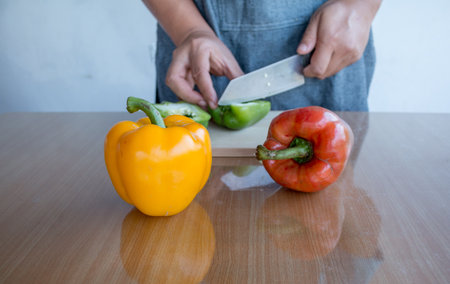 Fresh colorful bell pepper cooking on wooden cut board in kitchen table ready for cook.の写真素材