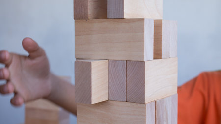 The tower from wooden blocks with kid's hand playing stack game.の写真素材