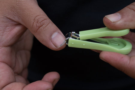 Closeup of man trims his fingernails using a metallic pair of nail clippers.の写真素材