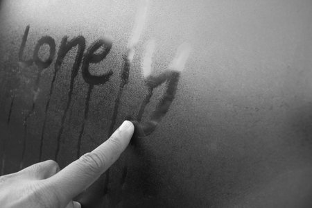 Women Hand's drawing "Lonely" word on glass window with water drop concept design for valentine's day or wedding background.の写真素材