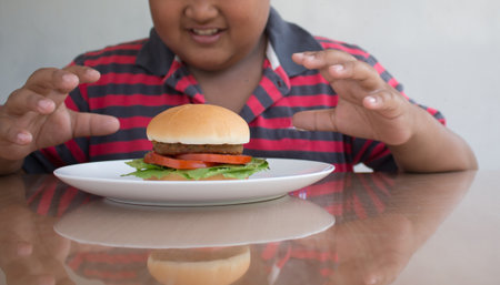 Asian boy's eating a hamburger, junk food unhealthy for children.の写真素材
