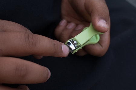 Closeup of man trims his fingernails using a metallic pair of nail clippers.の写真素材