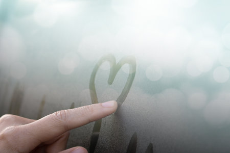 Women Hand's drawing Heart shape on glass window with water drop concept design for valentine's day or wedding background.の写真素材