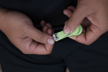 Closeup of man trims his fingernails using a metallic pair of nail clippers.の写真素材
