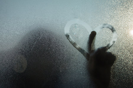 Womem Hand's drwing Heart shape on glass window with waterdrop concept design for valentine's day or wedding background.の写真素材