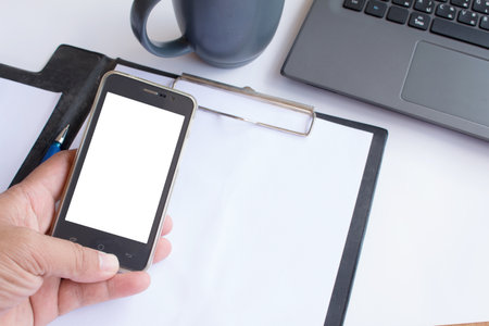 Asian man holding his blank smartphone during work in office.の写真素材