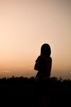 Asian woman silhouette over sunset.の写真素材