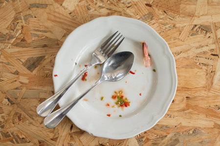 Closeup of Empty white dish with fork and spoon after eating on the table.の写真素材