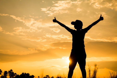 Girl lifting her hands up in the air across the field .の写真素材