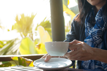 A Business woman is holding a white coffee cup.