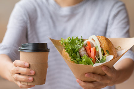 The waitress serves A Burger with coffee to customer.の写真素材