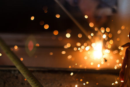 Bokeh light from sparks, labour welding steel in the industry plants. image for background.