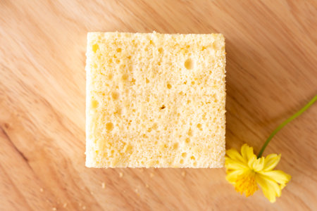 Homemade sponge cake on wooden plate decorate with cute yellow flower in coffee's shop.の写真素材