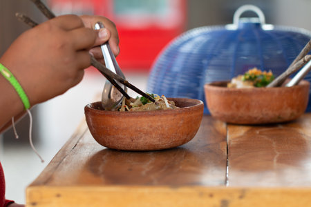 An Asian people is eating noodles on wooden table.の写真素材