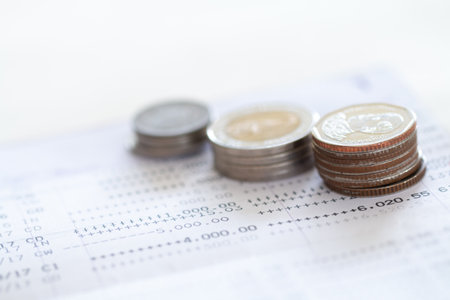 Selective focus of Thai's coins stacked over page of Bank account statement on  white background,...