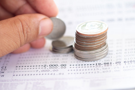 Selective focus of Thai's coins stacked over page of Bank account statement on  white background, Collecting money for investment concept with copy space.の写真素材