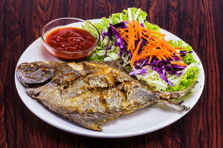 Fried fish with garlic tasty seafood on white plate wooden tableの写真素材