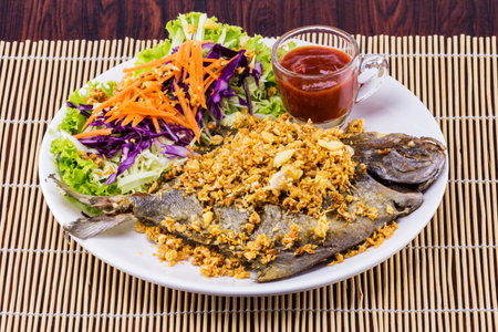 Fried fish with garlic tasty seafood on white plate wooden tableの写真素材