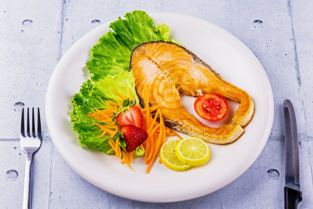 Salmon steak with vegetable on white plateの写真素材